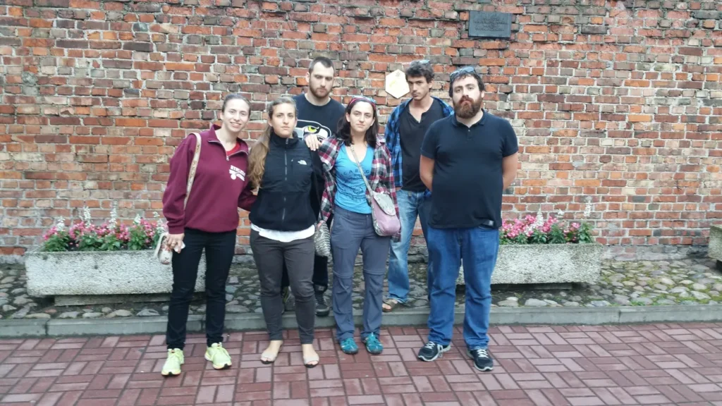 Esther, Elisheva, Shoshana, Aleksander, Jack and Micha standing before the remnant of the Warsaw ghetto wall.